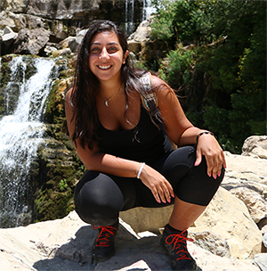 Krystel sits in front of a waterfall looking fit and athletic