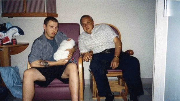 Scott holds his baby daughter while seated by his father